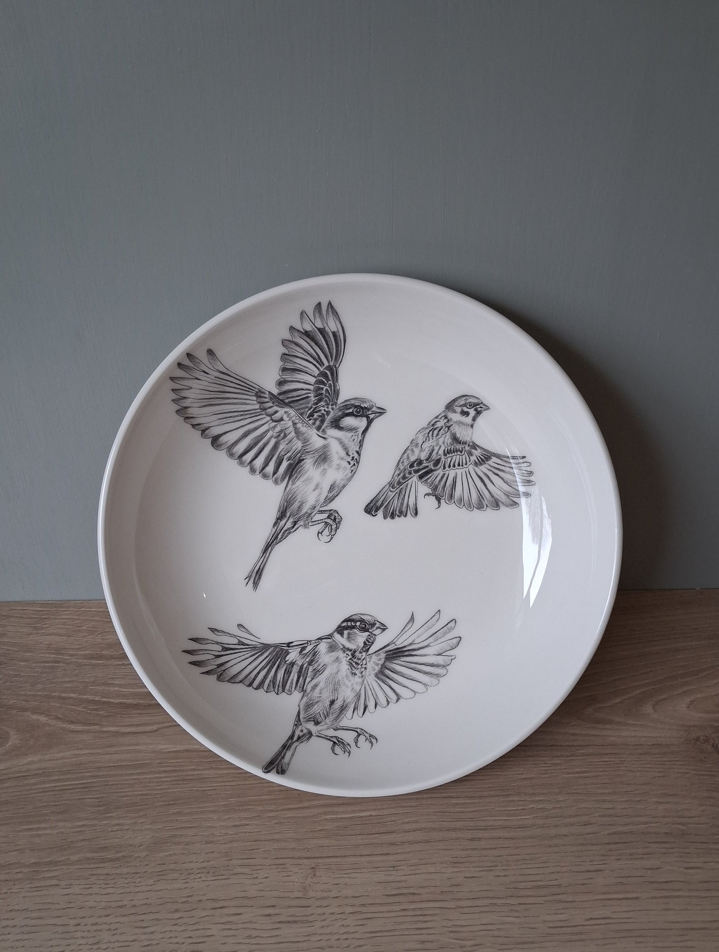 Wite ceramic serving bowl with hand drawn image of 3 sparrows in flight.