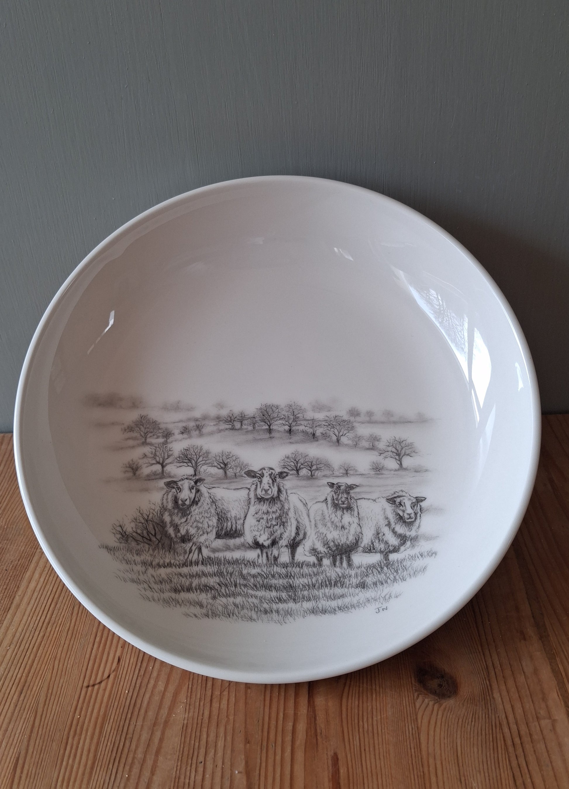 White ceramic bowl with a hand drawn image of sheep in a Dartmoor setting.