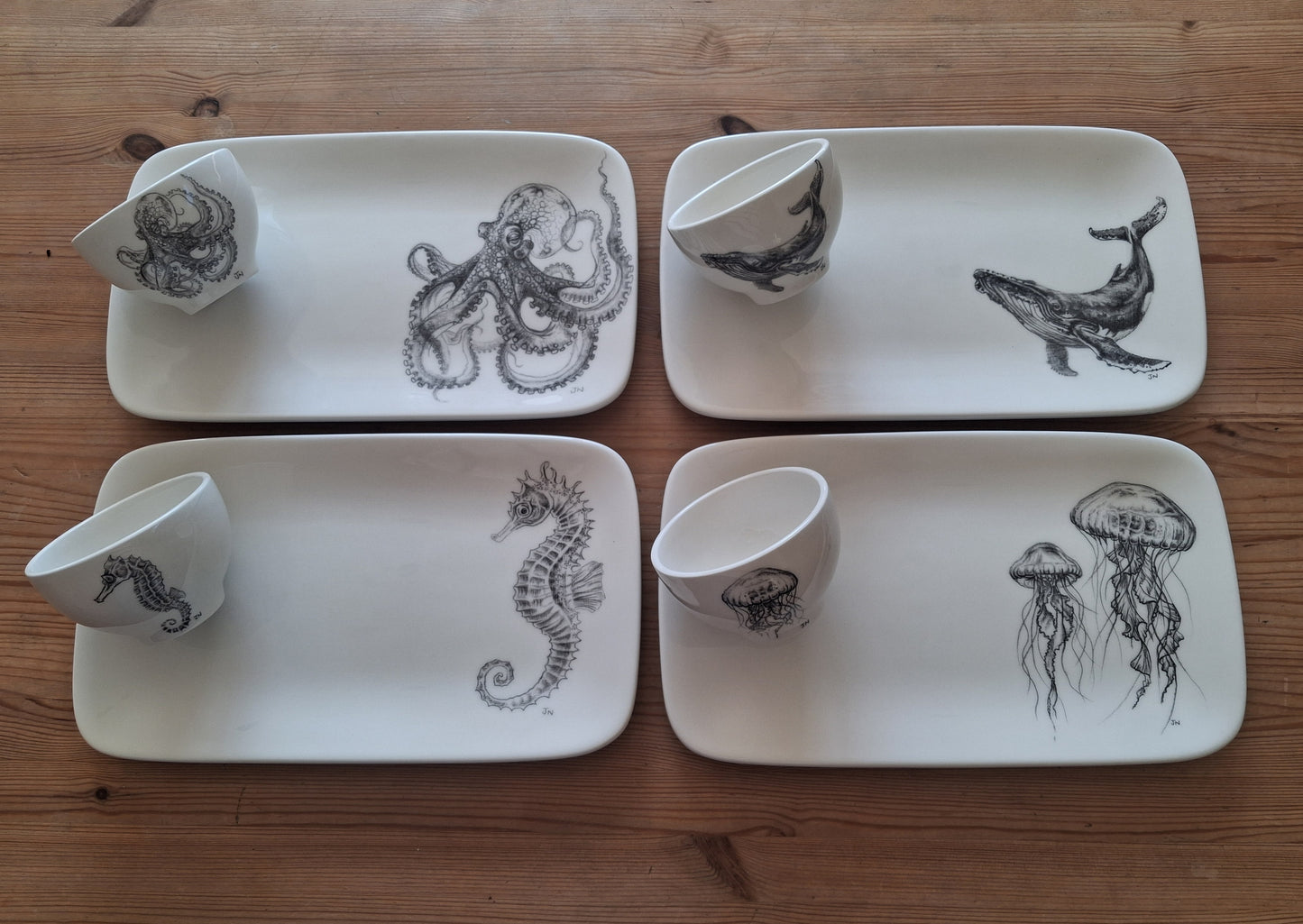 Set of 4 rectangular ceramic serving platters with small round dipping bowls. Each platter and bowl decorated with a hand drawn image of an ocean creature.