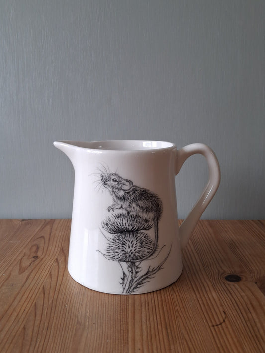 White ceramic milk jug with hand drawn image of a mouse sitting on top of a thistle.